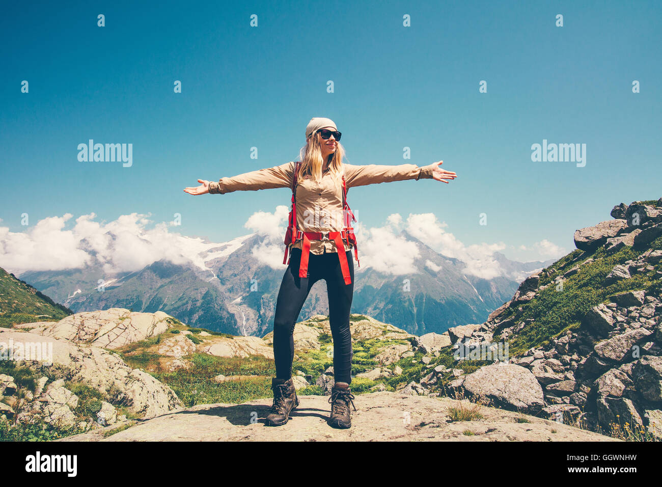 La donna le mani alzate con zaino rilassante con le montagne e le nuvole paesaggio sullo sfondo di viaggio il concetto di stile di vita attivo summ Foto Stock