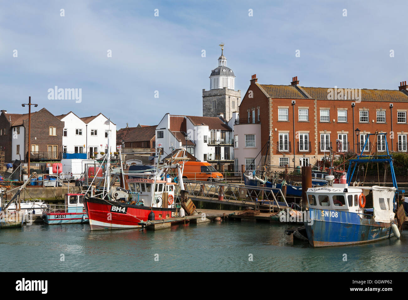 Affollato porto di pesca nella vecchia Portsmouth. Fila di barche ormeggiate nei bacini di campanatura. La torre della cattedrale in background. Foto Stock