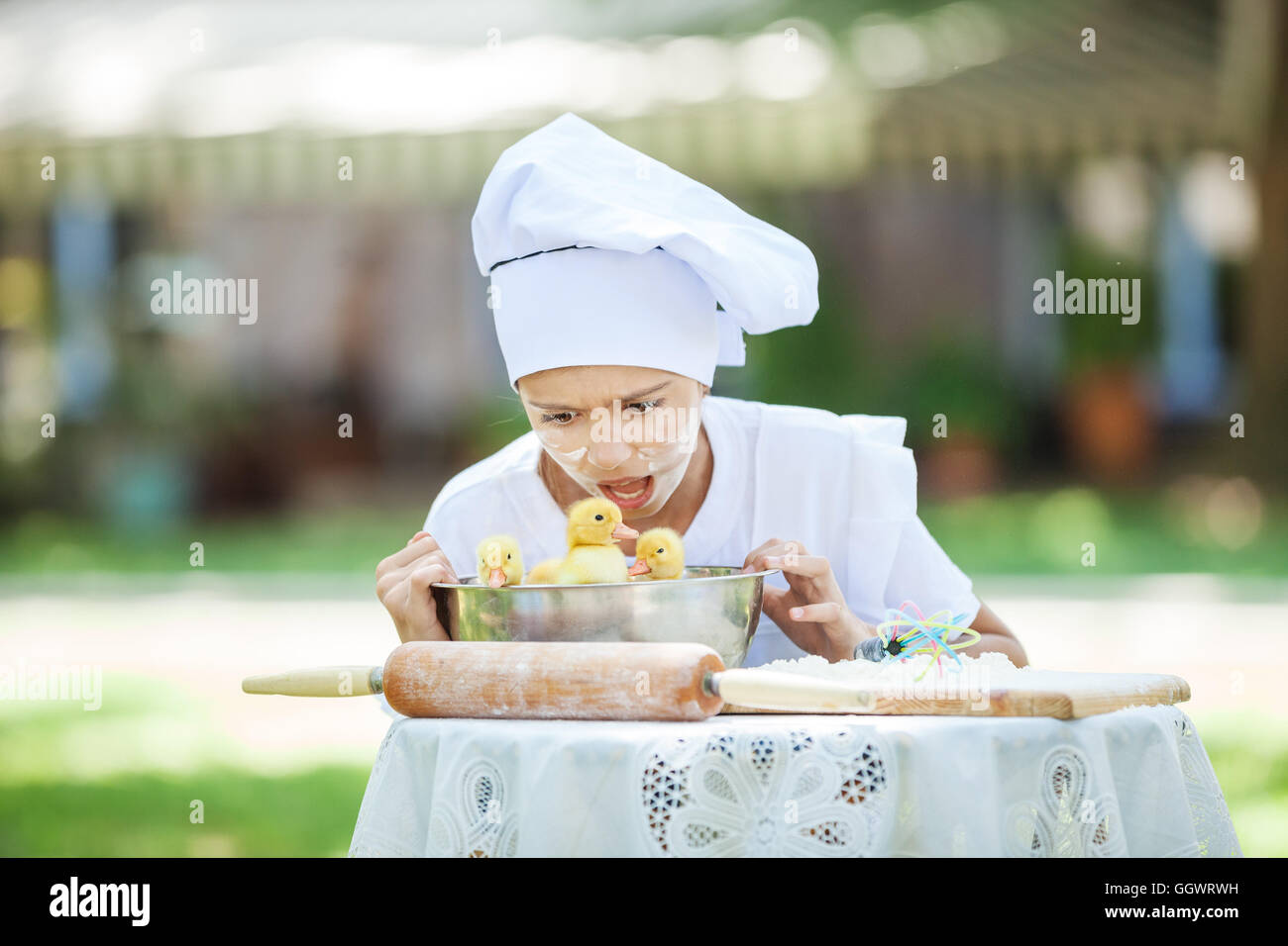 Scioccato little chef che mostra le ochette in un recipiente durante la cottura all'aperto Foto Stock