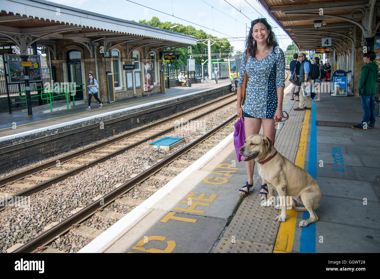 Donna con cane in attesa a Berkhamsted stazione ferroviaria per i treni per Londra Foto Stock