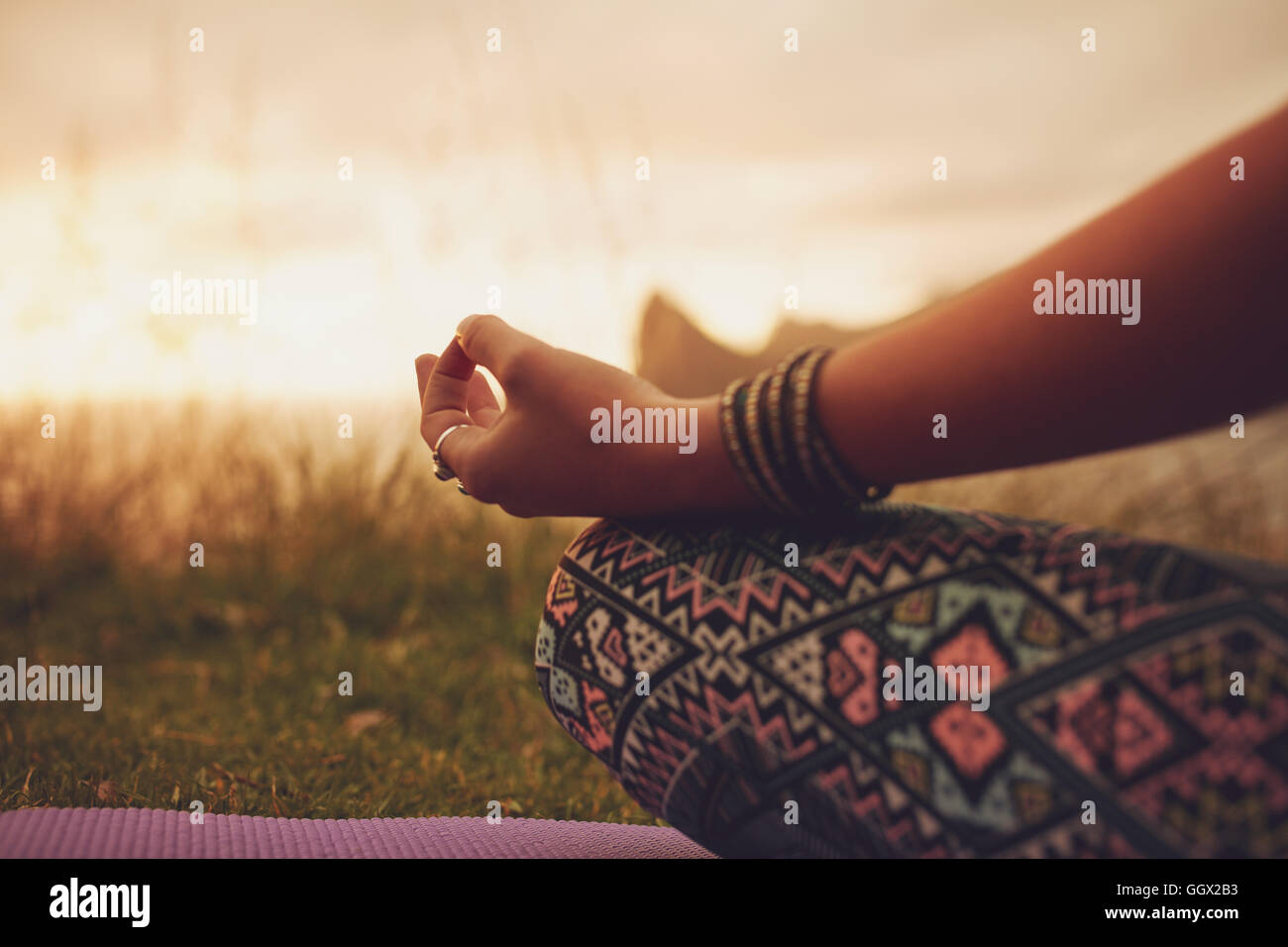 Primo piano di una donna in posa di loto, con attenzione alle mani. fitness femminile che medita all'aperto durante il tramonto. Foto Stock