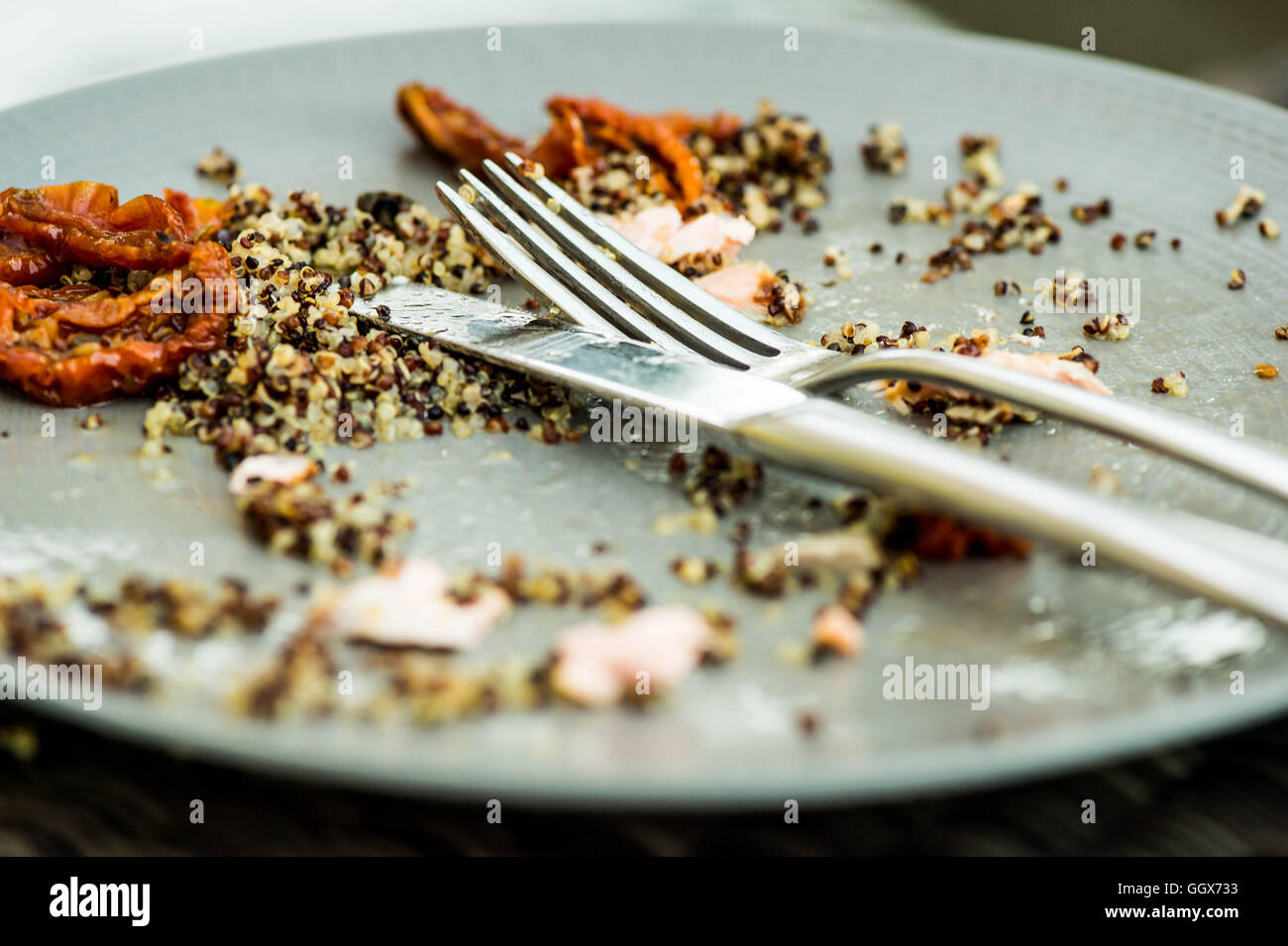 Cibo left overs su una piastra con un coltello e forchetta dopo la finitura di un pasto Foto Stock