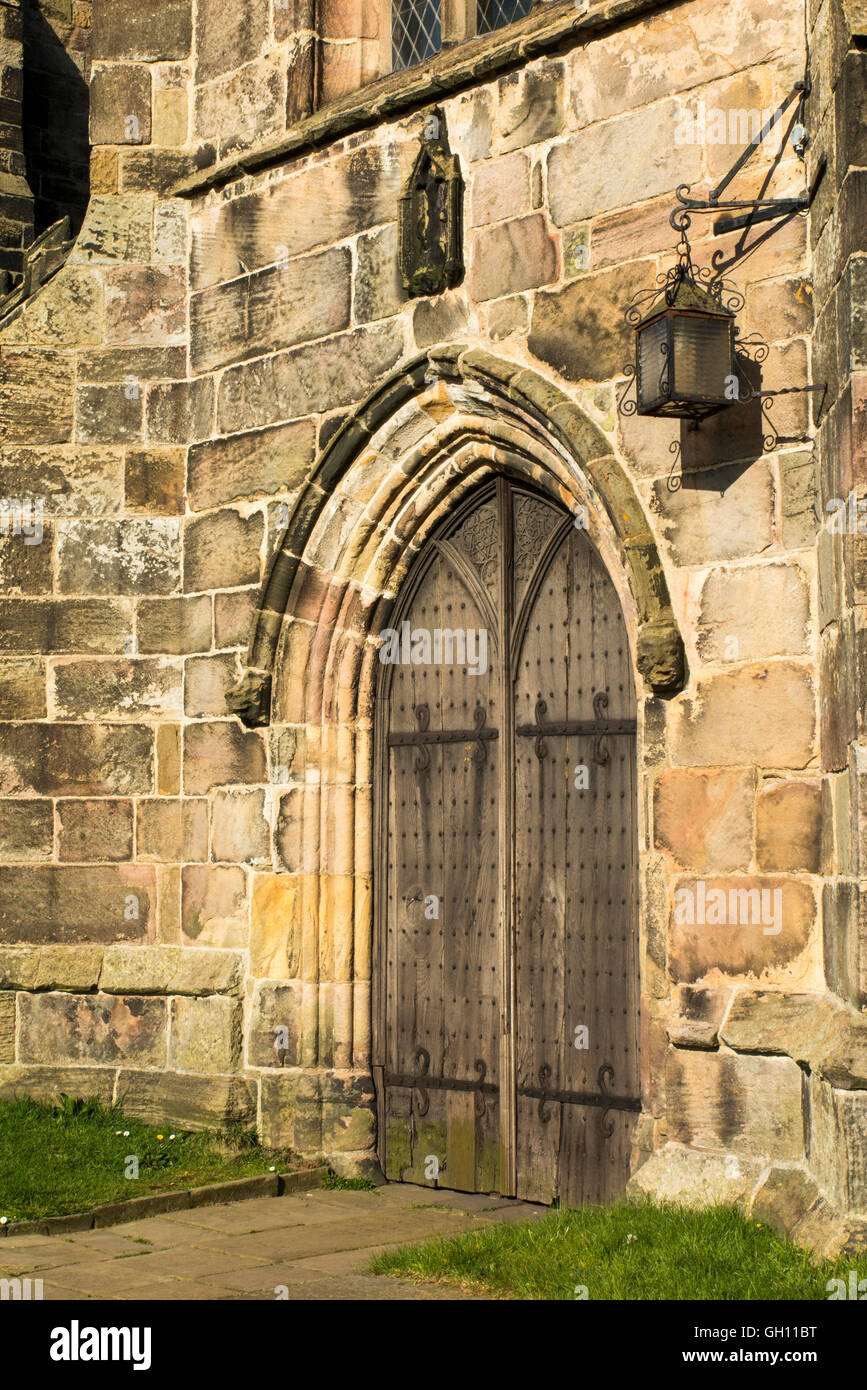 Regno Unito, Inghilterra, Cheshire, Astbury, Chiesa di Santa Maria, pesanti porte in legno di quercia e lampada Foto Stock