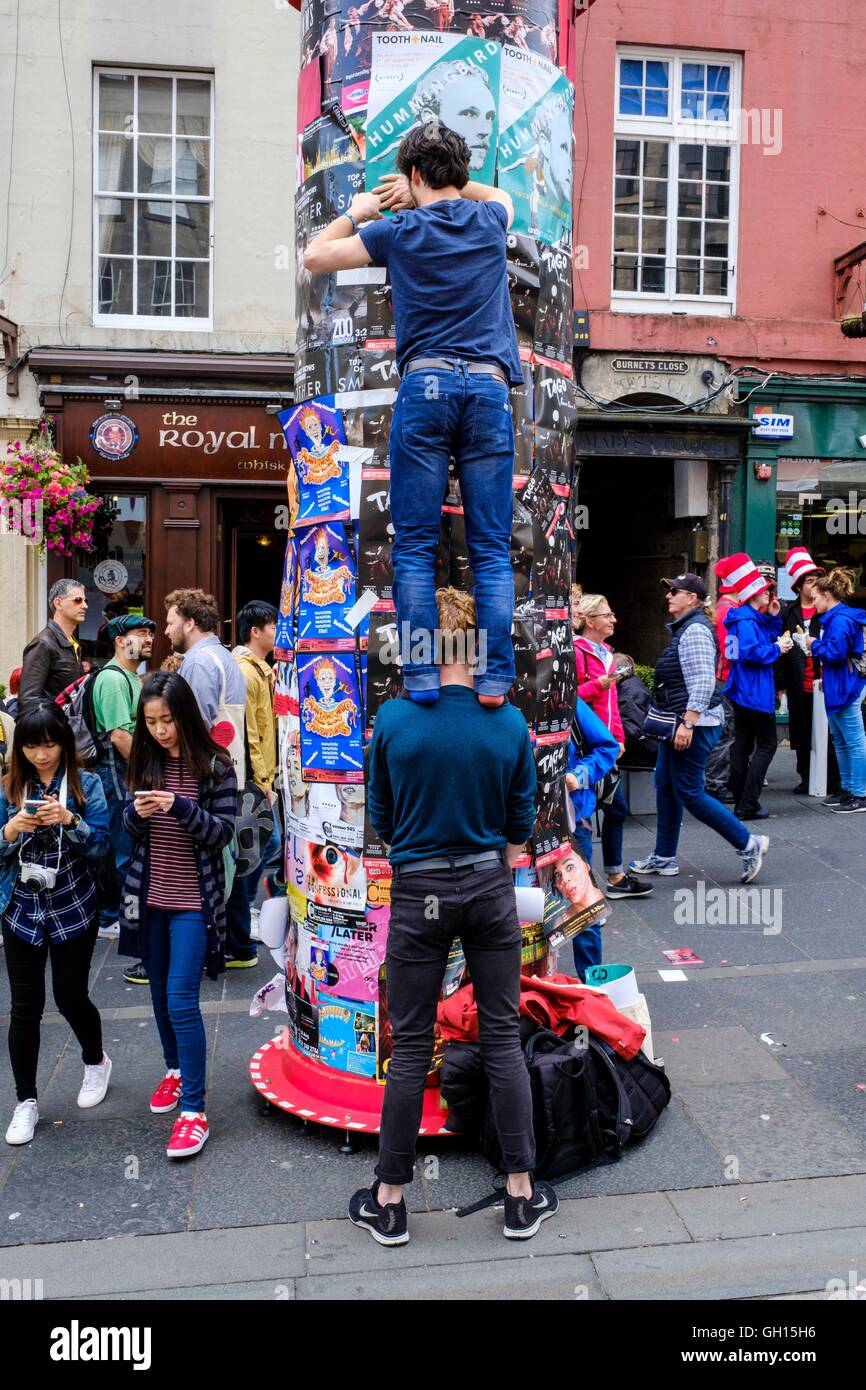 Edimburgo, Scozia, Regno Unito. Il 7 agosto, 2016. Interpreti di Fringe mostra intrattenere in High Street per promuovere i loro spettacoli. Un esecutore collocando un poster per il suo spettacolo su un pilastro nella High Street Credit: Andrew Wilson/Alamy Live News Foto Stock