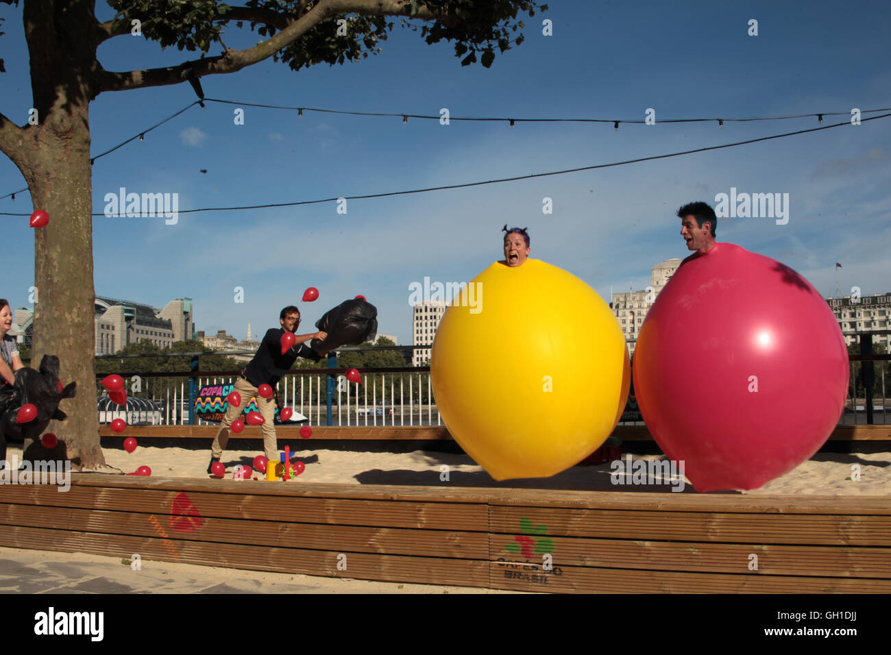 Londra, Regno Unito. 8 agosto, 2016. New York clown duo Acrobuffos eseguendo una parte dell'aria Play, parte del Southbank del Festival di amore dal 9 agosto al 14, sul centro il cosiddetto Copacabana Beach. Il duo, Seth Bloom e Christina Gelsone, sarà in esecuzione visualizza con battenti ombrelloni, palloncini e aquiloni. Credito: Roger Garfield/Alamy Live News Foto Stock