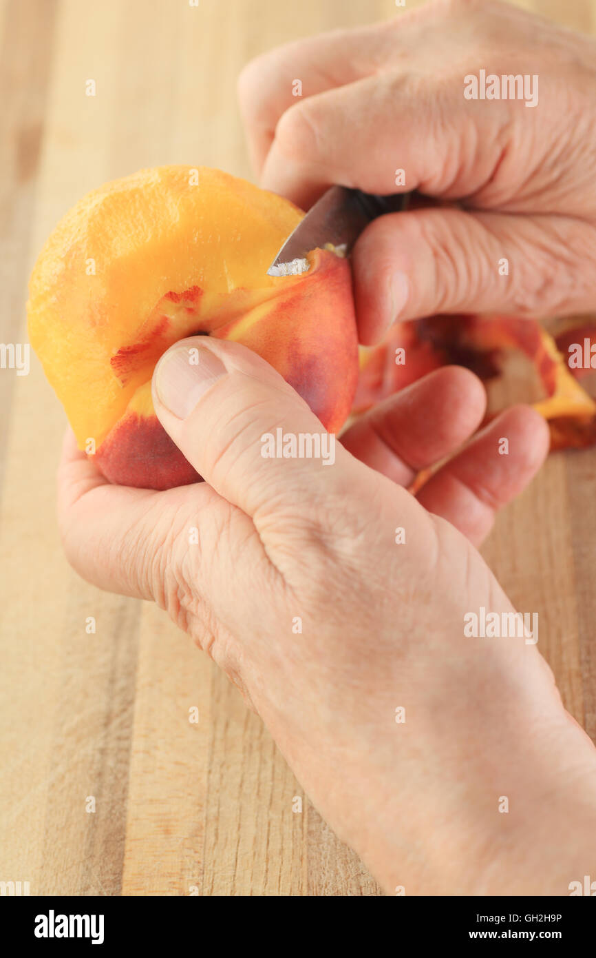 Il punto di vista dell'uomo peeling un pesche fresche Foto Stock