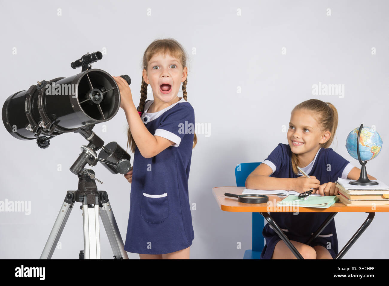 Ragazza sorpreso astronomo osservando attraverso un telescopio, l'altra ragazza guardò Foto Stock