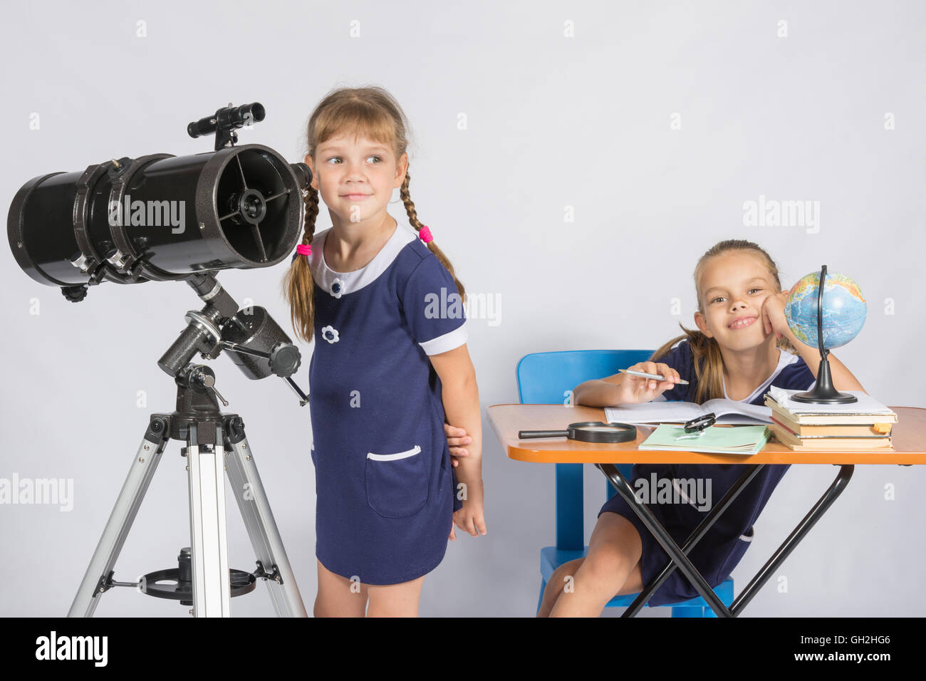 Astronomo ragazza guarda al cielo, l'altra ragazza seduta felicemente al tavolo Foto Stock