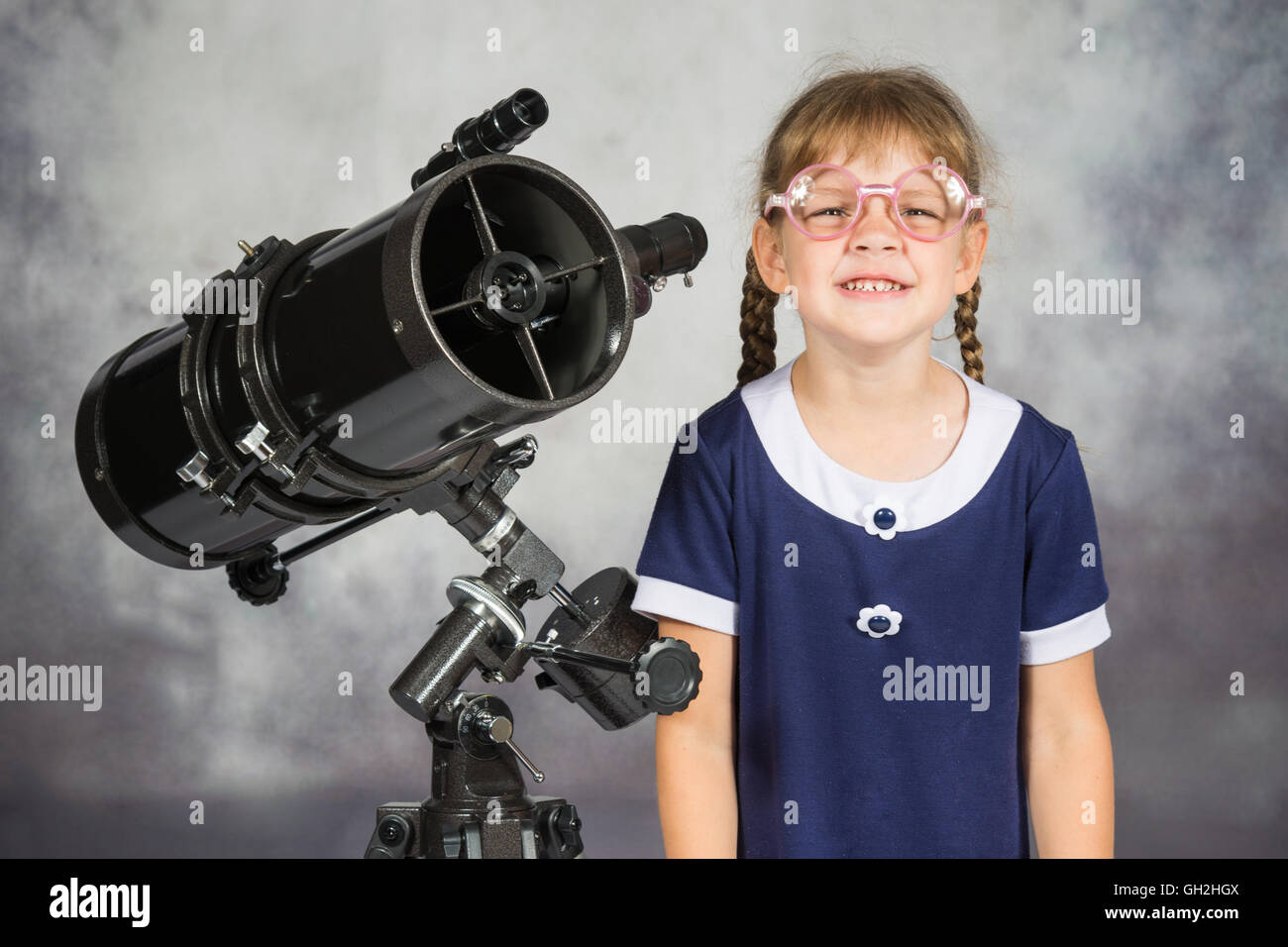 Ragazza bespectacled astronomo dilettante funny sorridente in piedi dal telescopio Foto Stock