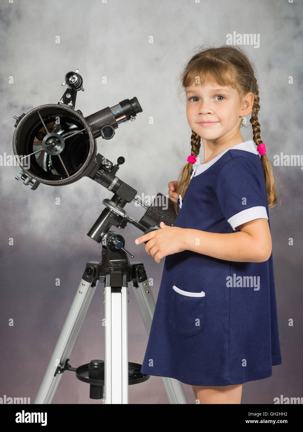 Ragazza amante di astronomia sorge accanto al telescopio e guardato dentro il telaio Foto Stock