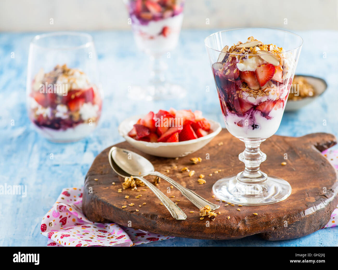 Yogurt con fragole, noci e semi di lino in vetro su tavola di legno, fuoco selettivo Foto Stock