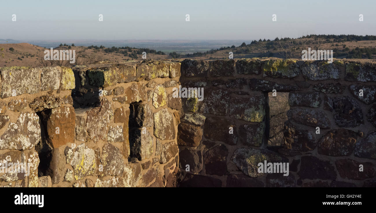 Una roccia muro di castello si affaccia su colline basse. Foto Stock