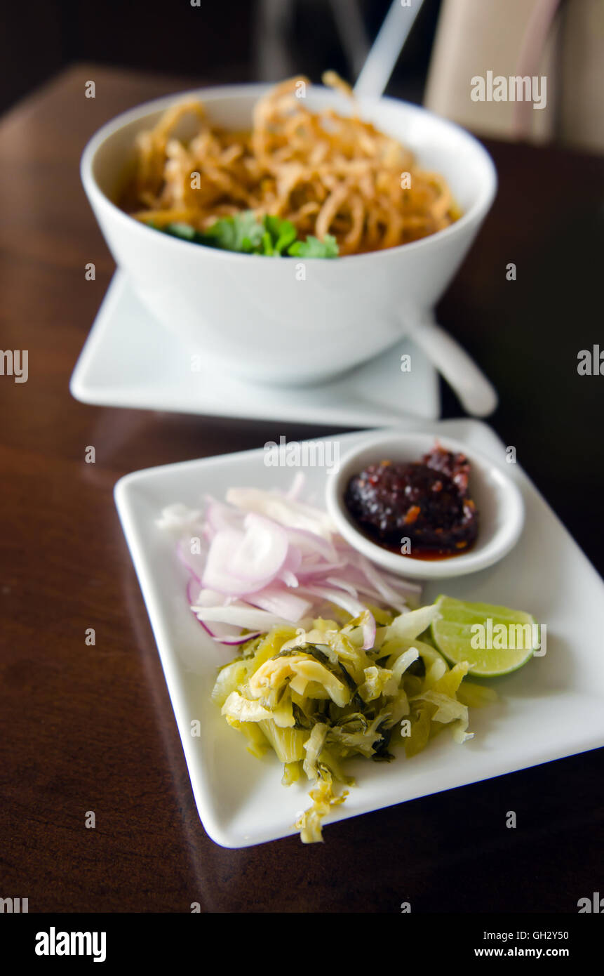 Khao Soi ricetta, Thailandia stile settentrionale salsa speziata zuppa di noodle al pollo con servita con verdure, calce e pasta di peperoncino Foto Stock