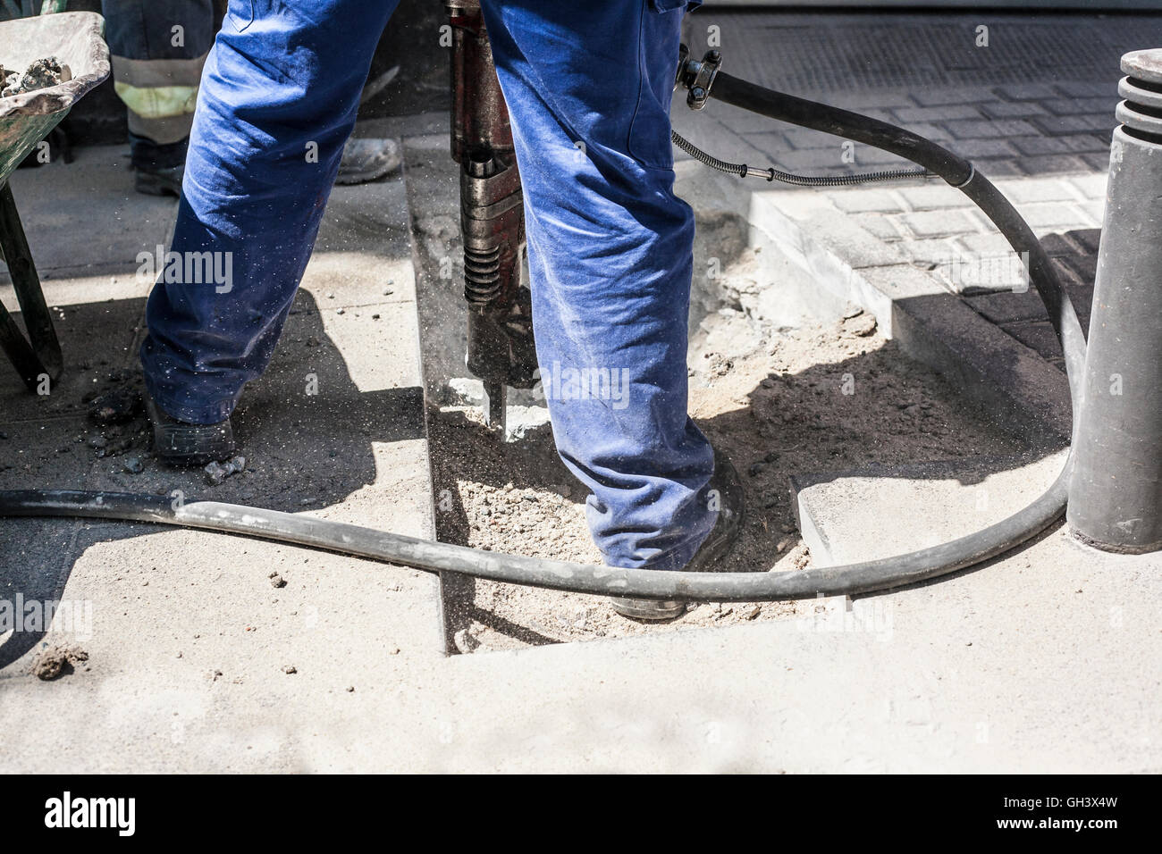 Builder lavoratore con martello pneumatico attrezzatura di perforazione rottura asfalto marciapiede sulla strada Foto Stock