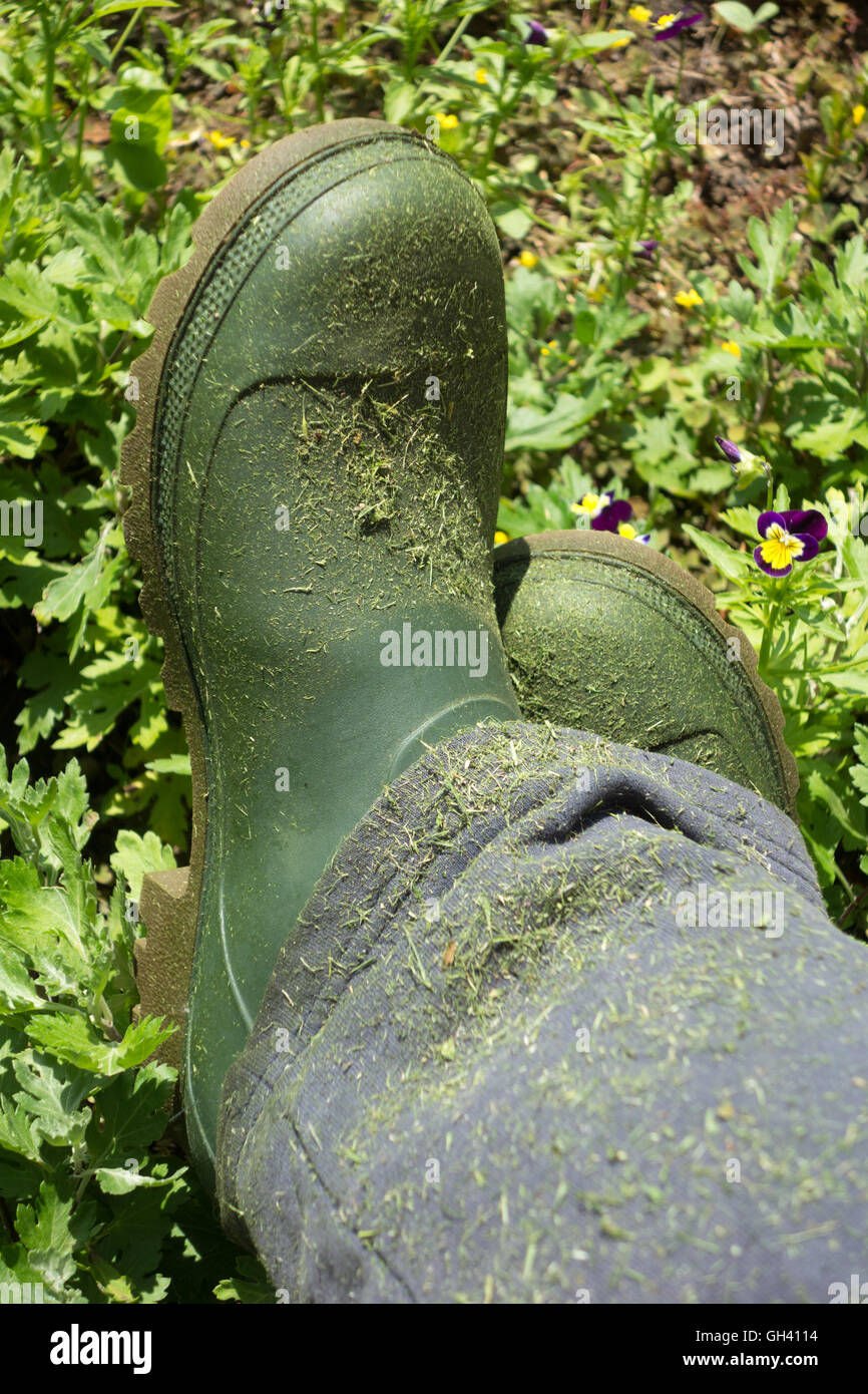 Coltivatore urbano verde stivali gardering sopra lo sfondo del giardino Foto Stock