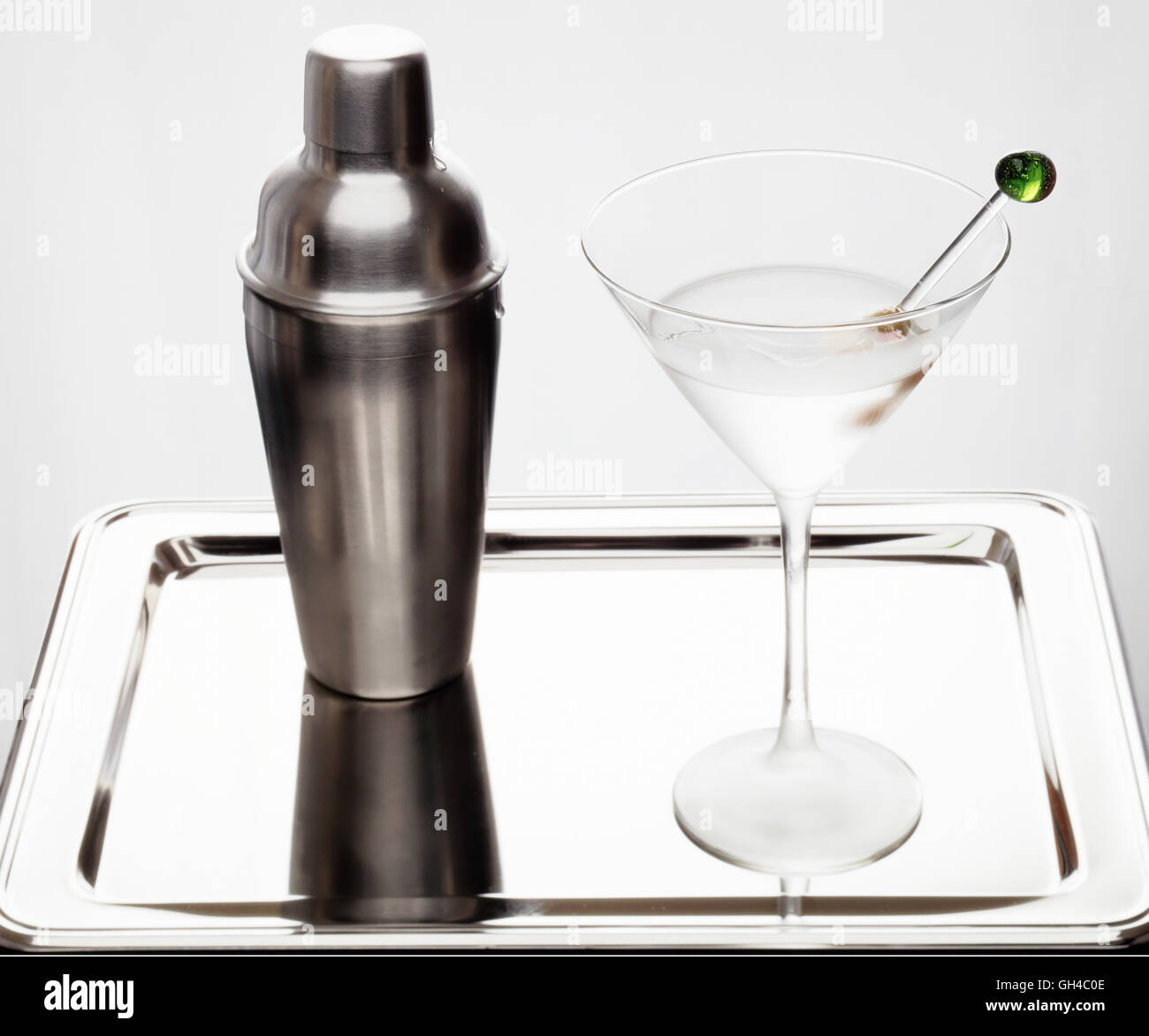 Elevato La chiave ad alto angolo di visione di una sporca Martini in un gelido vetro con Olive verdi con un agitatore su un vassoio Foto Stock