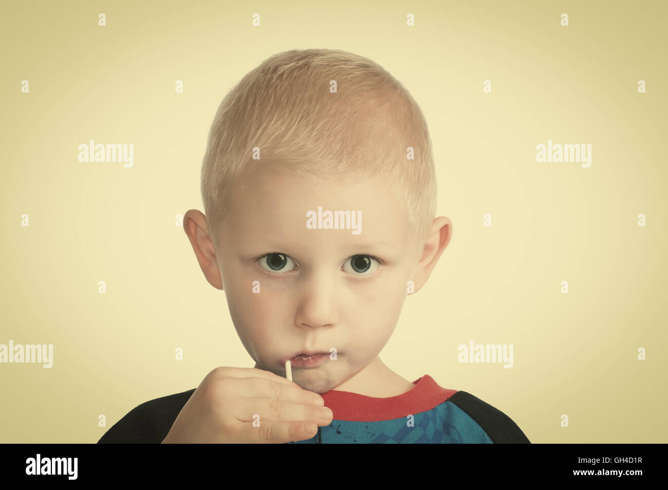 Grazioso piccolo ragazzo biondo con una ventosa nella sua bocca. Retrò instagram look. Foto Stock