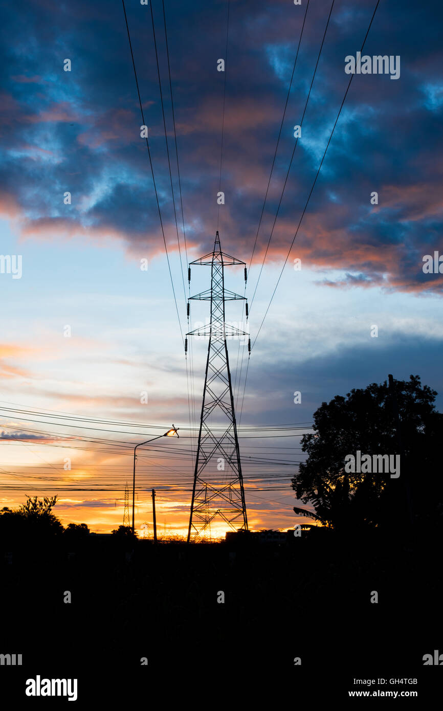 Pilone elettrico sagome in un tramonto. Sfondo Foto Stock