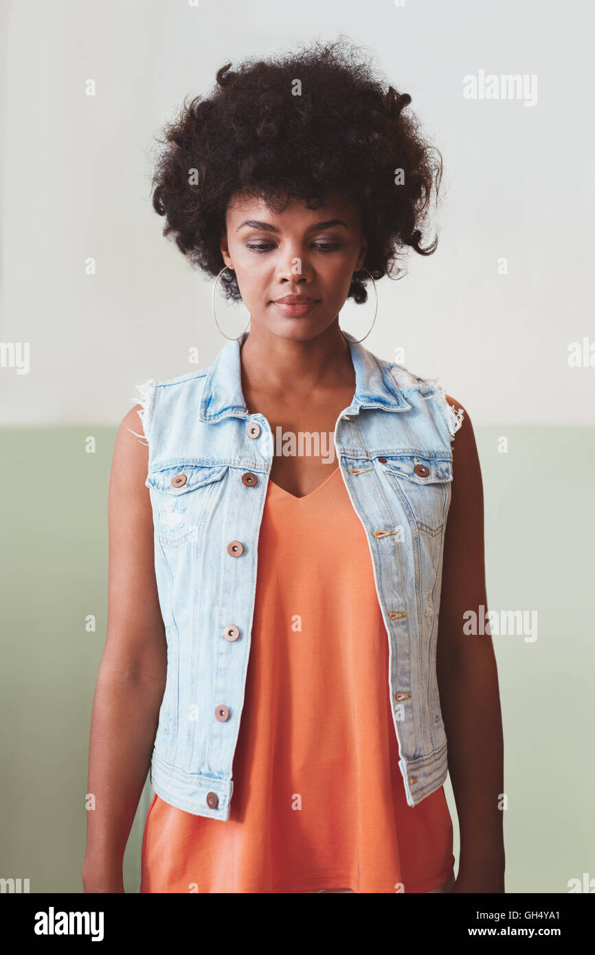 Ritratto di attraente giovane donna in piedi da solo. African modello femminile guardando verso il basso. Foto Stock