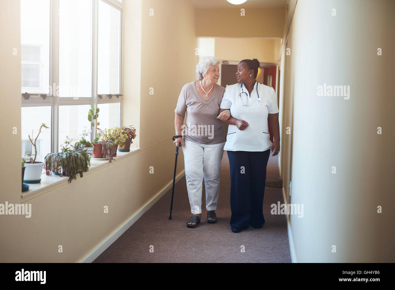A piena lunghezza ritratto di donna senior a piedi con la sua balia presso la casa di cura. Attività sanitarie aiutare paziente femmina. Foto Stock