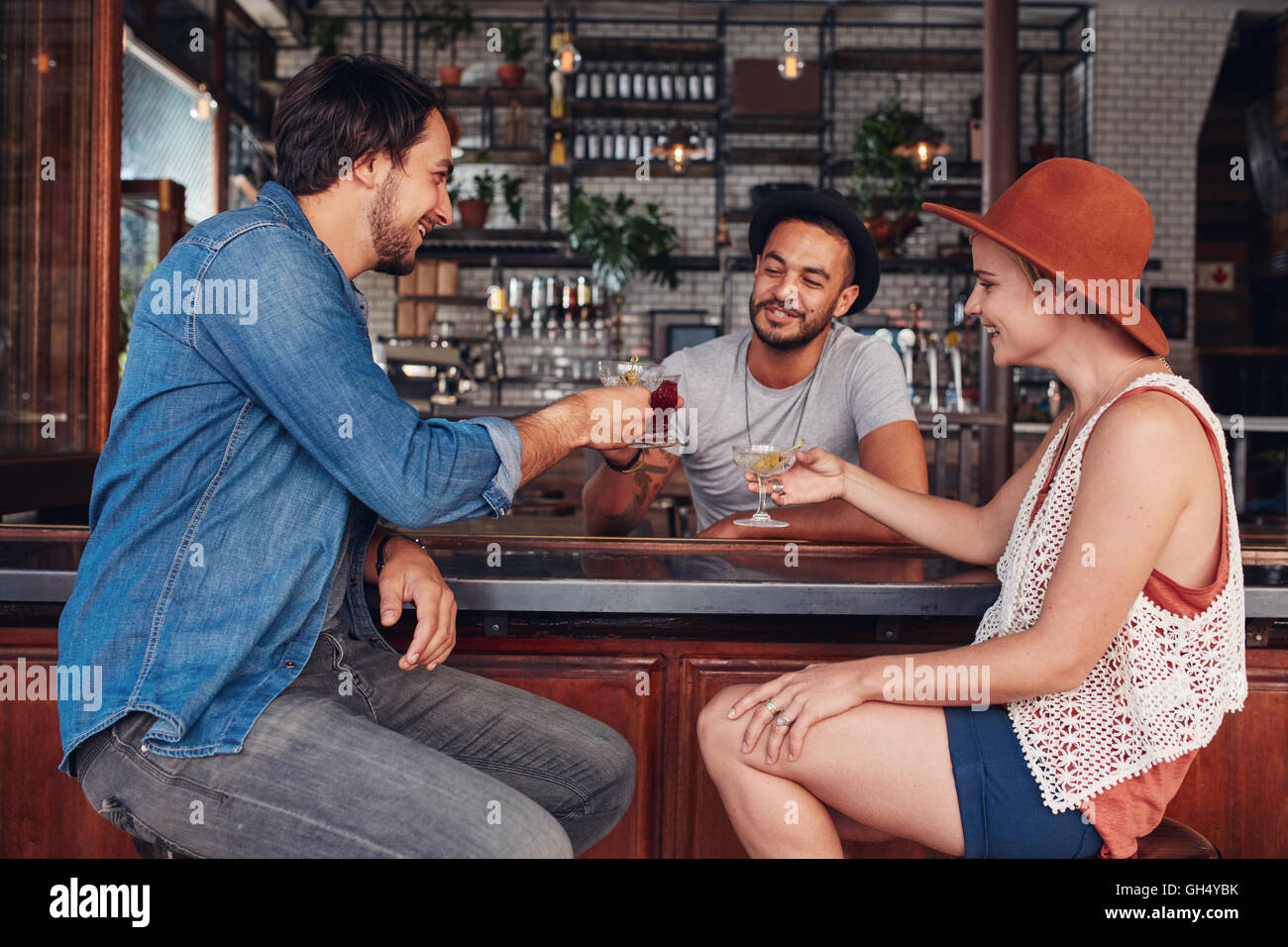 Ritratto di giovane gente moderna seduto in un coffee shop e aventi le loro bevande. Gruppo di amici in un bar di bevande di tostatura. Foto Stock