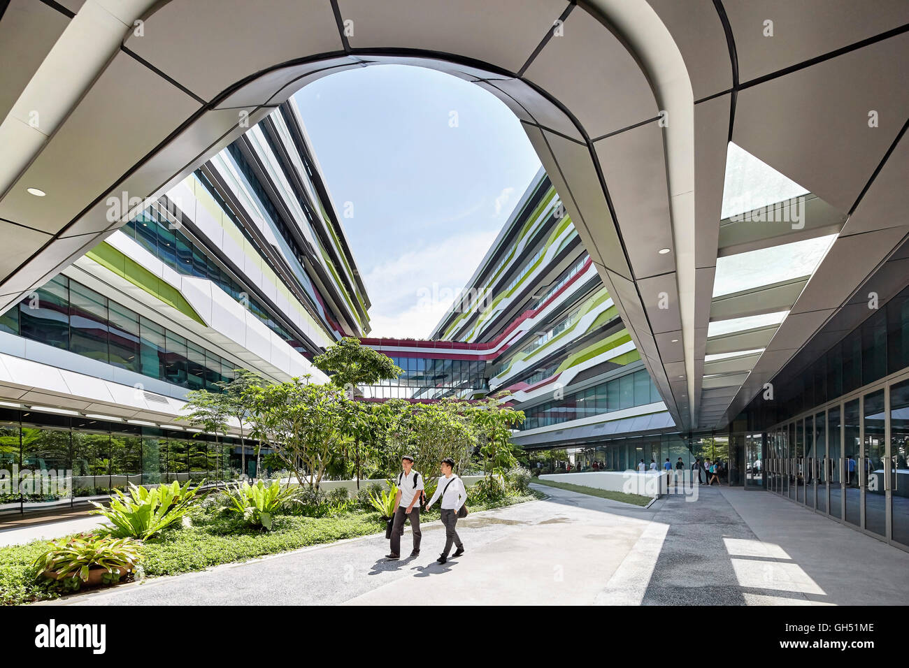 Aprire il cortile interno con giardino e camminamenti e edificio curvo facciate. Università di Singapore di tecnologia e design, Singapore, Singapore. Architetto: UNStudio, 2015. Foto Stock