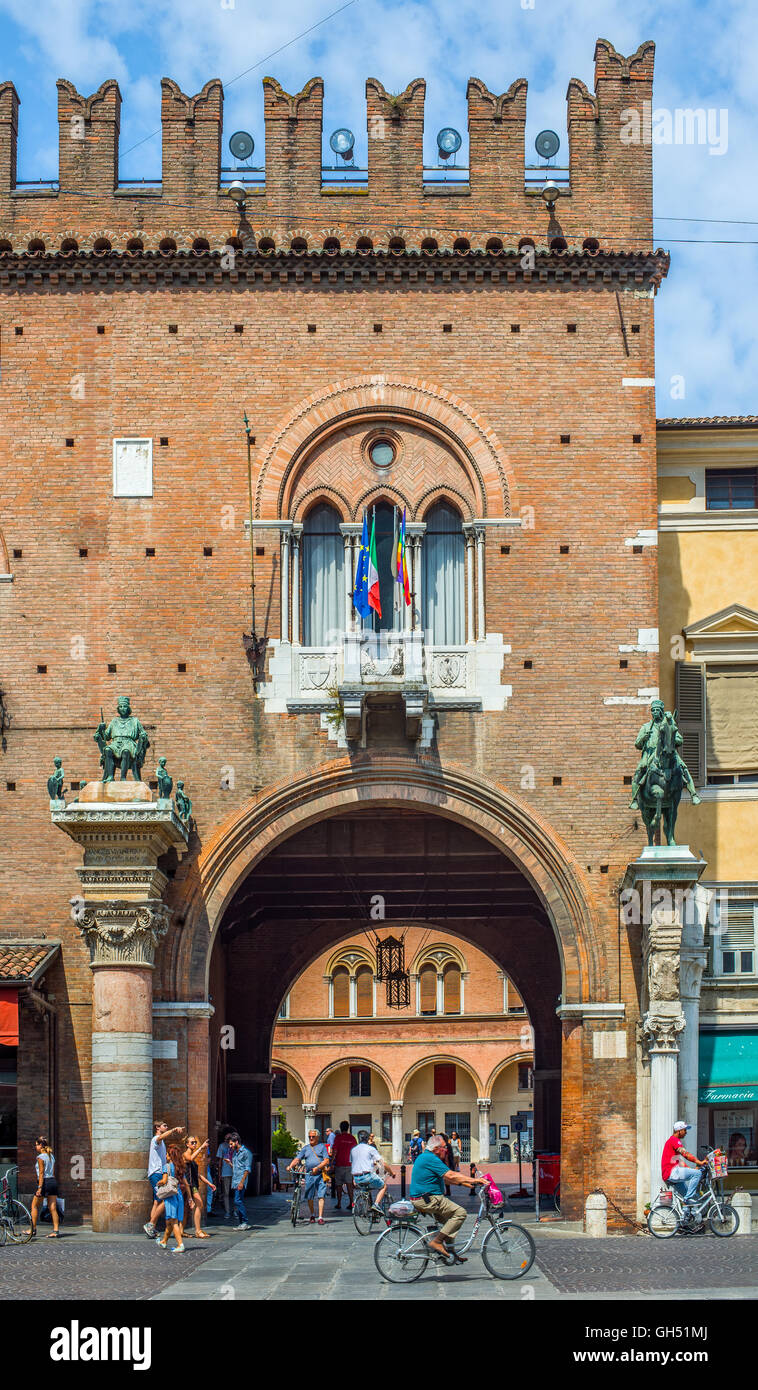 I ciclisti e le persone che attraversano la piazza del Municipio con il Palazzo Ducale di Estense ora Guildhall, a Ferrara, Italia Foto Stock