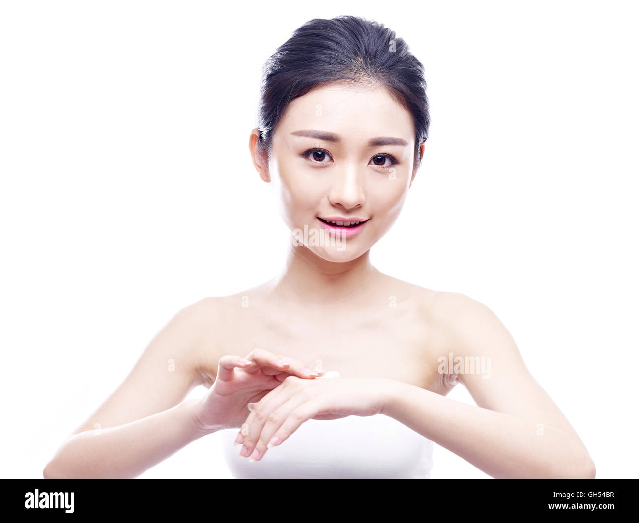 Giovane donna asiatica di applicare la crema lozione, isolati su sfondo bianco. Foto Stock