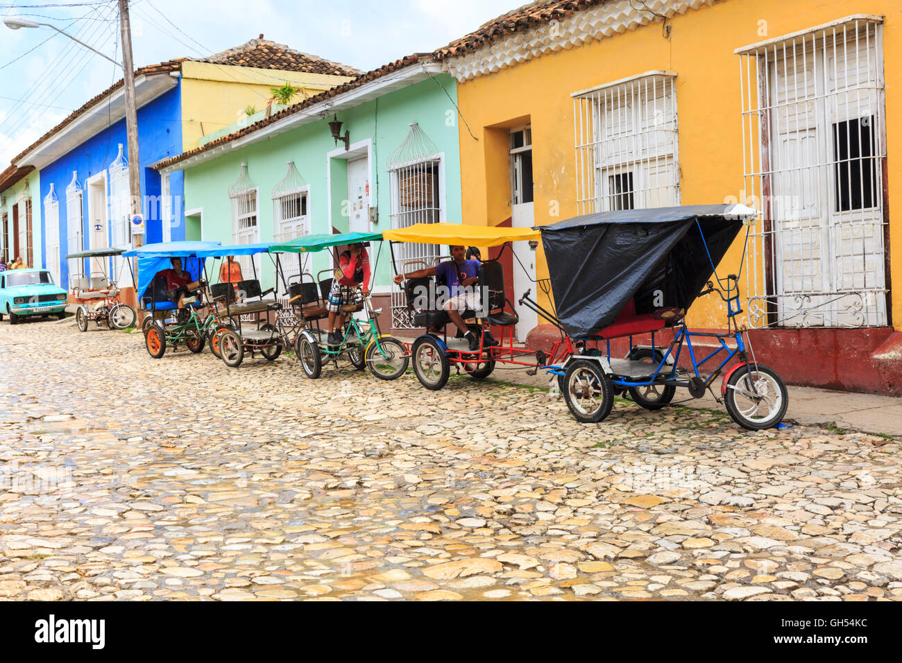 Trinidad street scene - bicitaxis cubano o ciclo taxi schierate in attesa in una strada di ciottoli, Cuba Foto Stock