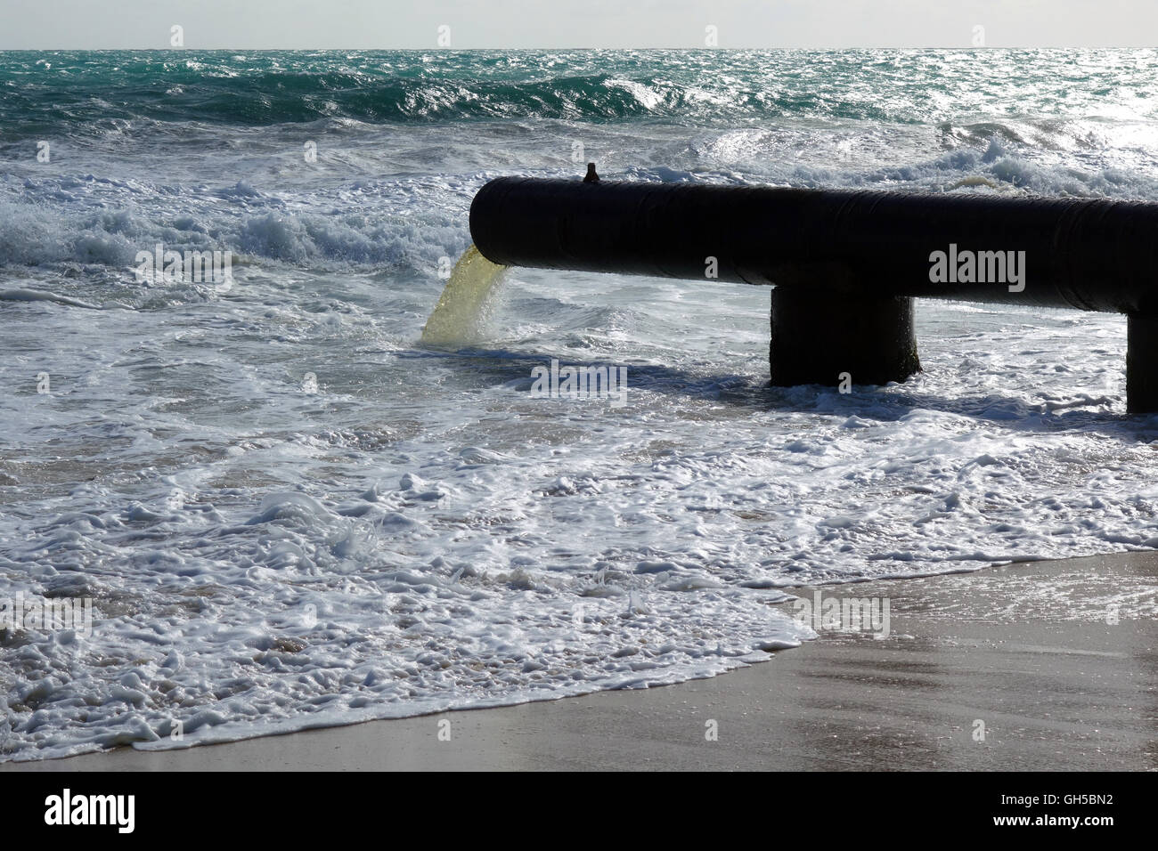 Tubazione di acque piovane che fluisce nell'oceano di fronte spiaggia Foto Stock