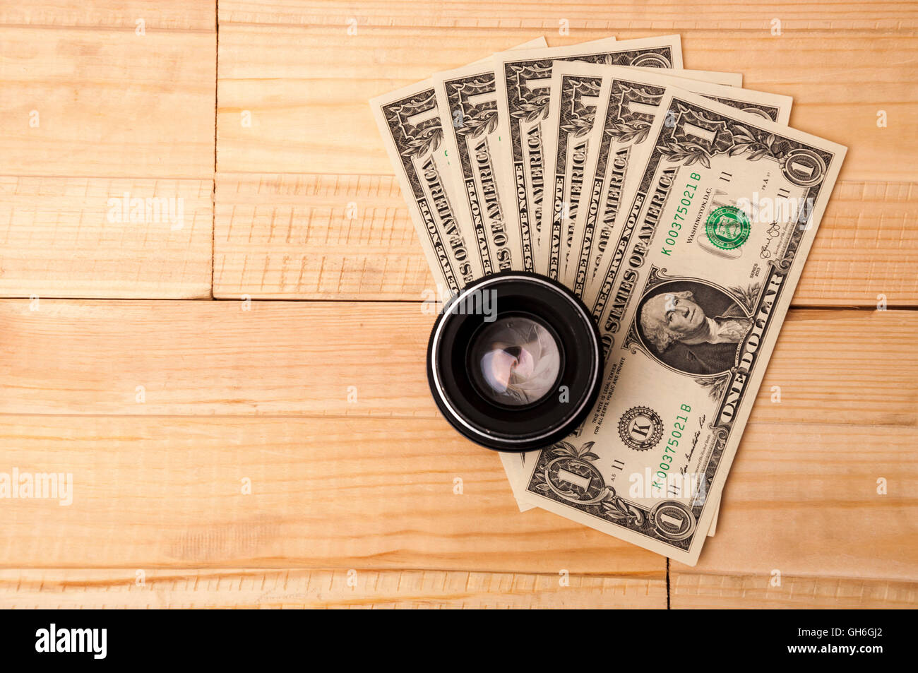Obiettivo fotografico con denaro su sfondo di legno. Acquisto di costose attrezzature fotografiche. Foto Stock