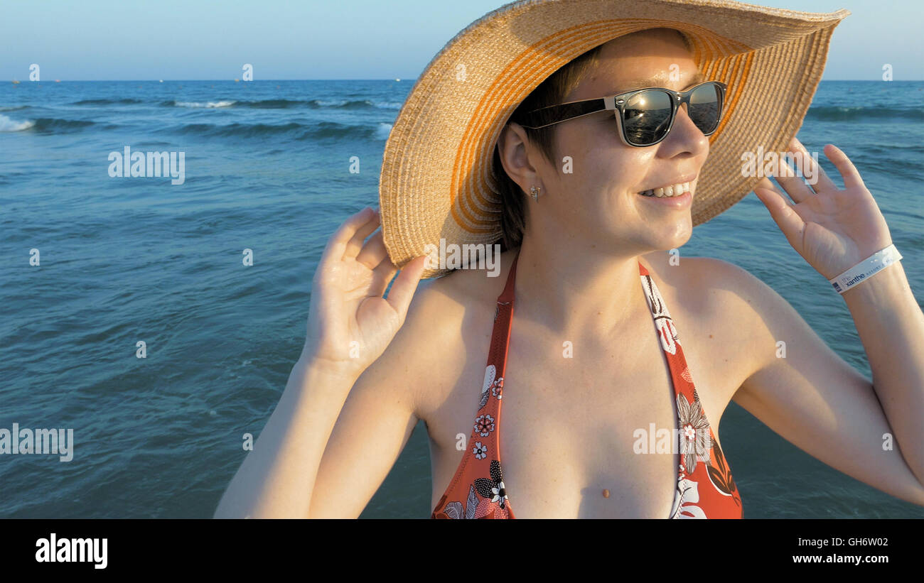 Femmina in occhiali da sole mettendo sul suo cappello Fedora Foto Stock