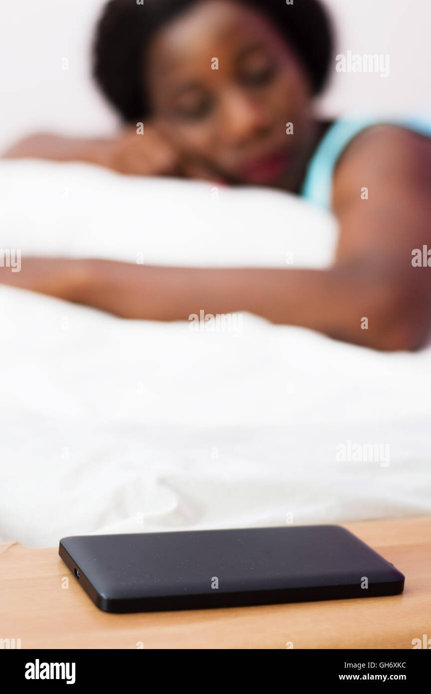 Il suo telefono cellulare depositata a portata di mano questa giovane donna è dormire profondamente. Foto Stock