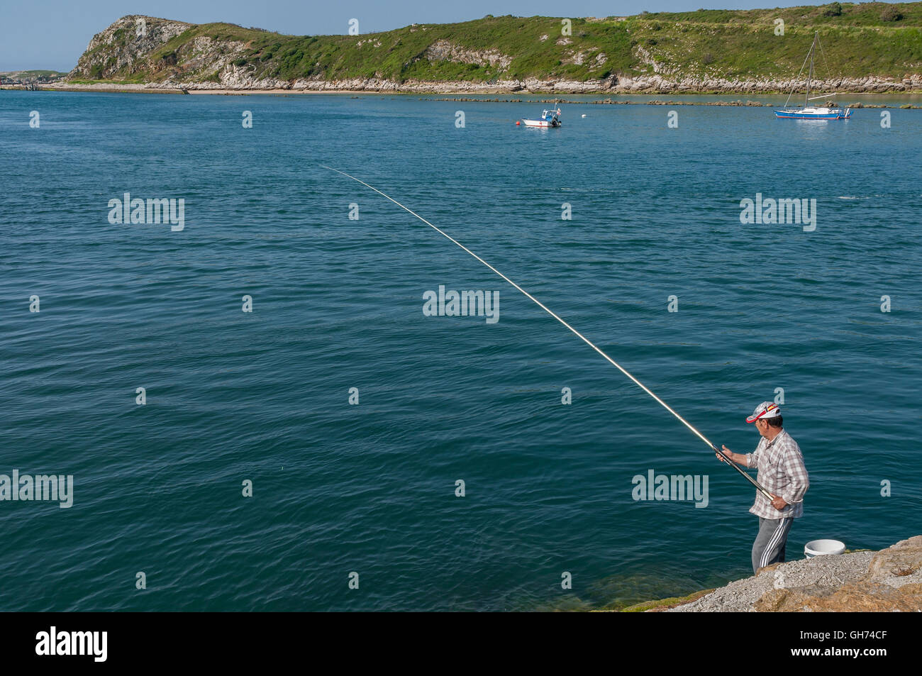 Uomo di pesca sul molo della saja e Besaya ria, nel villaggio di Suances Cantabria, Spagna. Foto Stock