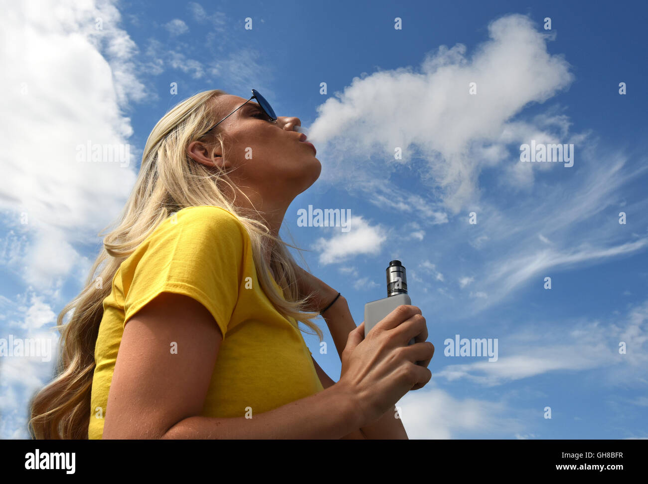Donna vaping femmina ed espirando vapore dalla sigaretta elettronica Foto Stock