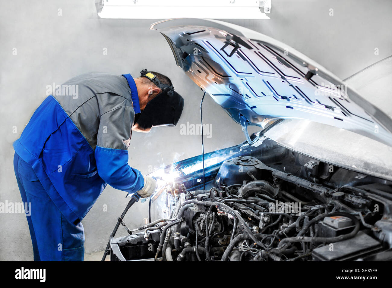 Professional repairman lavoratore nel settore automobilistico di saldatura del corpo metallico con auto scintille Foto Stock