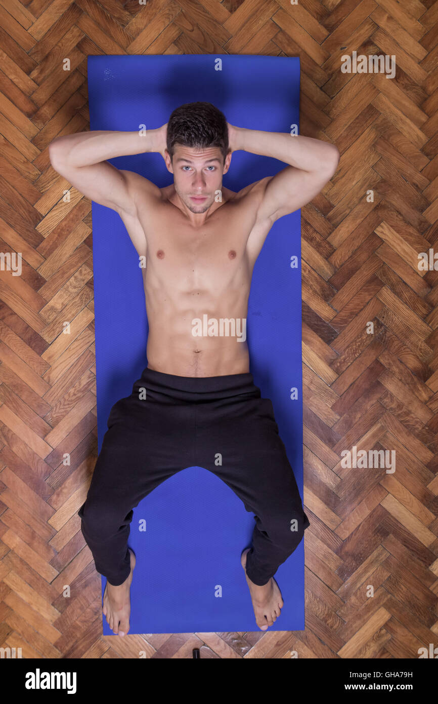 Montare slim abs bella giovane uomo che guarda verso l'alto vista in elevazione esercizio. Posa di mat Foto Stock