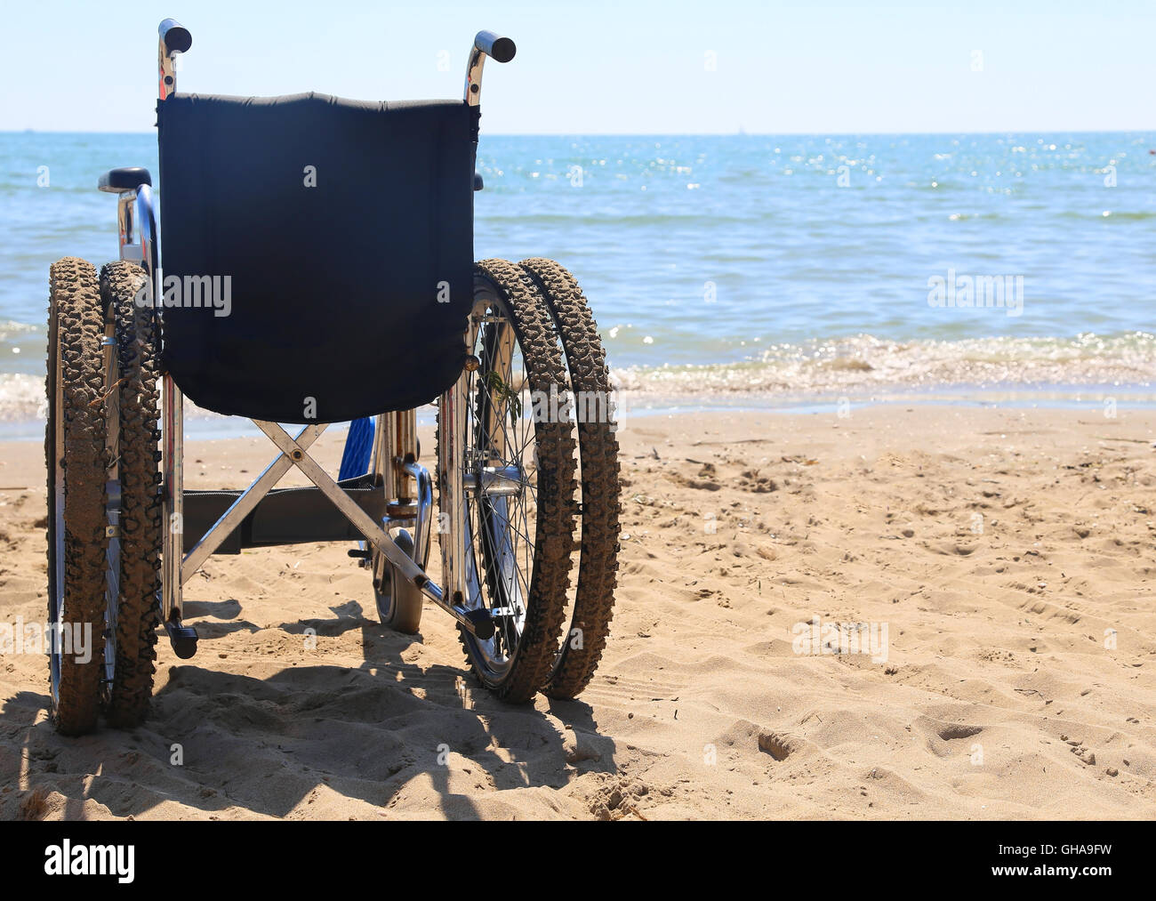 Sedia a rotelle dotata di pneumatici di tipo speciale per andare in spiaggia in riva al mare in estate Foto Stock