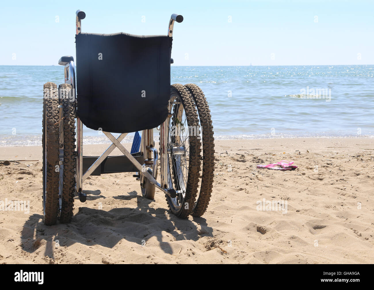 Sedia a rotelle sulla spiaggia in riva al mare in estate Foto Stock