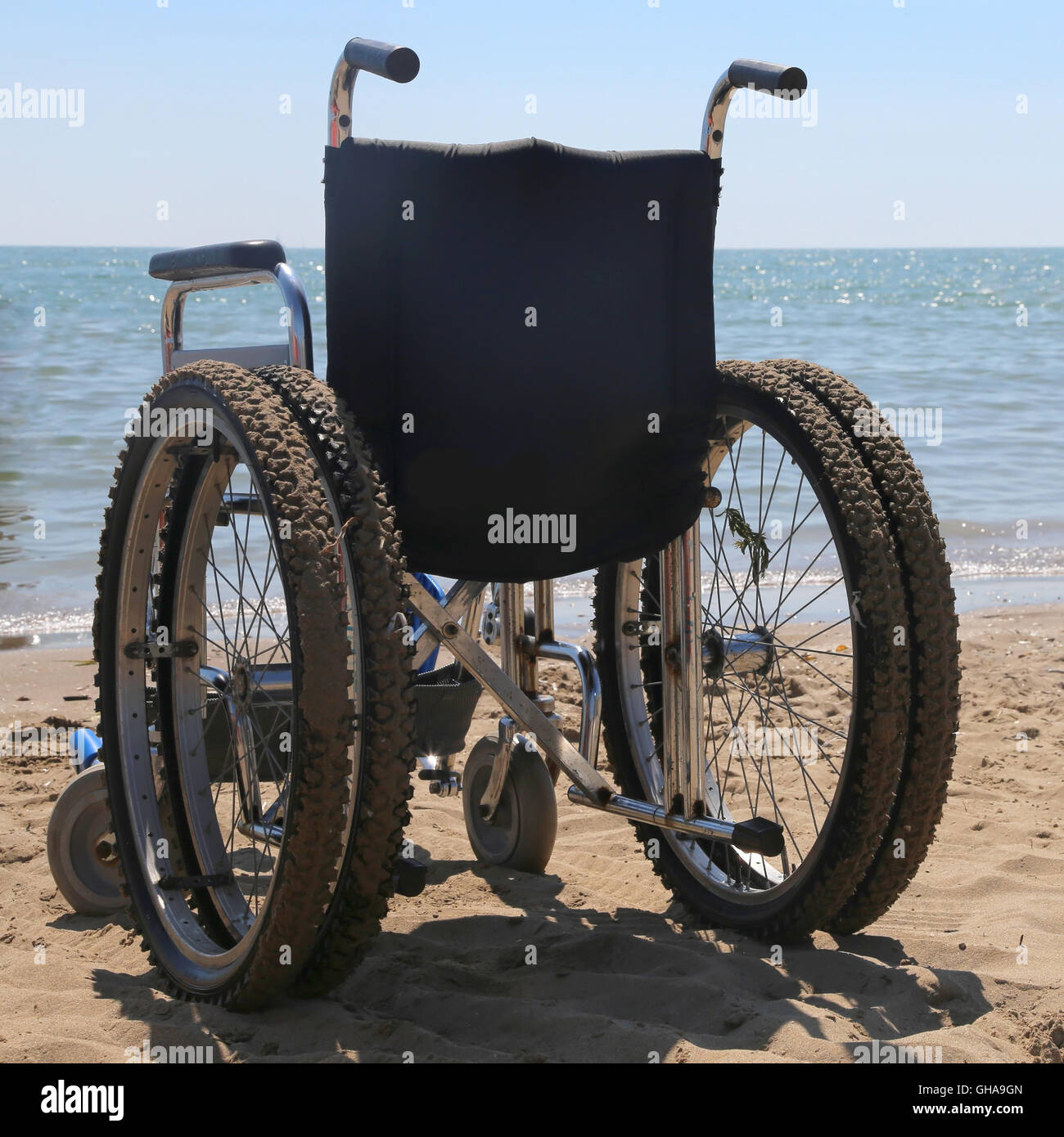 Sedia a rotelle sulla spiaggia di sabbia vicino al mare Foto Stock