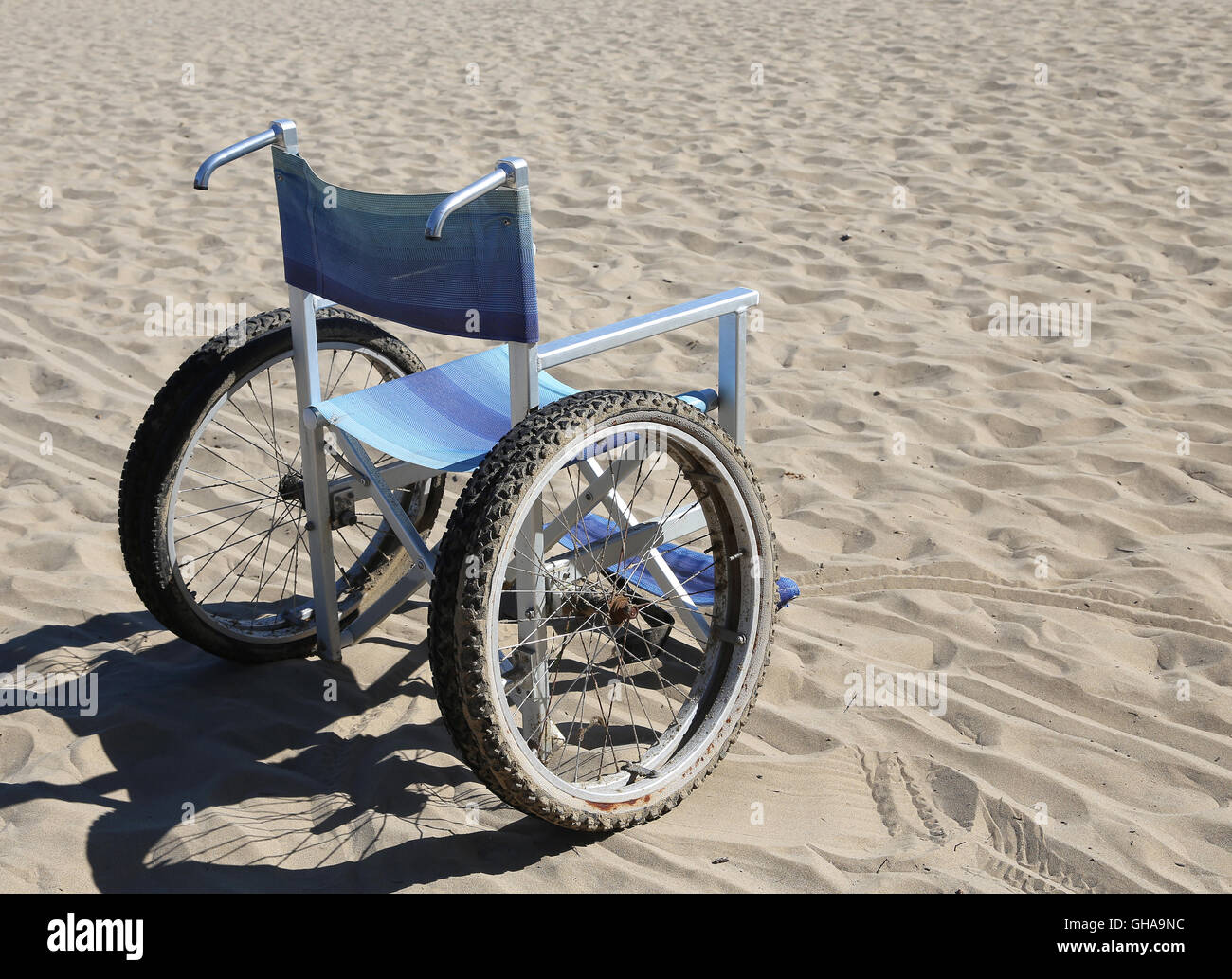 Sedia a rotelle sulla sabbia della spiaggia in estate Foto Stock