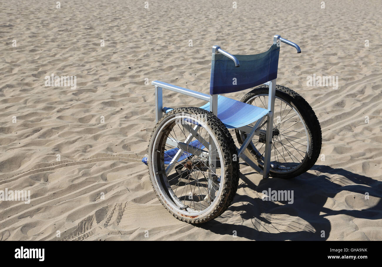 Sedia a rotelle isolato con ruote speciali sulla spiaggia di sabbia Foto Stock