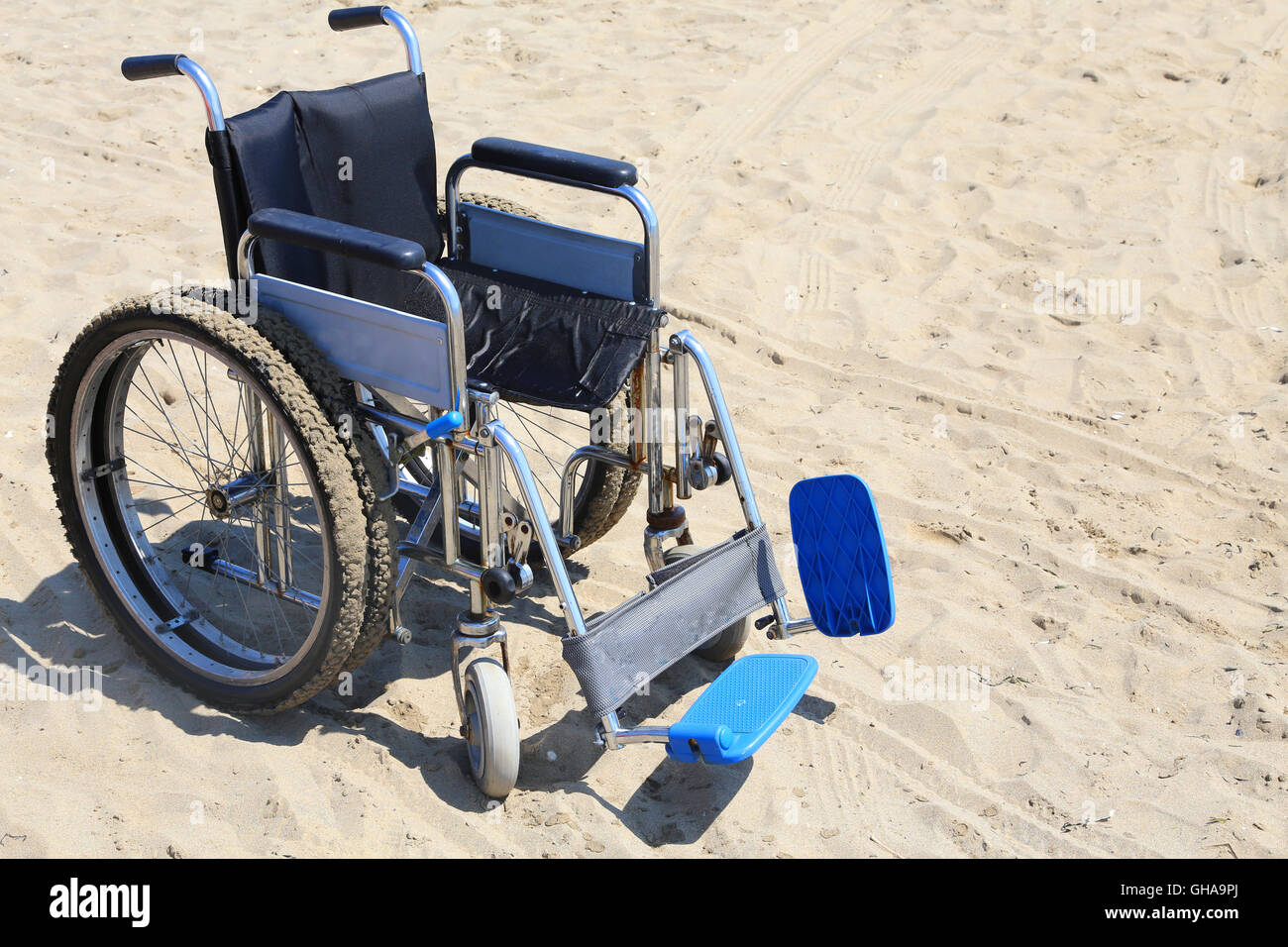 Sedia a rotelle di alluminio sulla sabbia della spiaggia in estate Foto Stock
