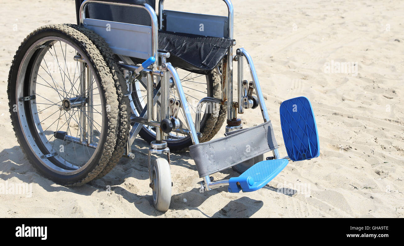 Sedia a rotelle sulla calda spiaggia sabbiosa in estate Foto Stock