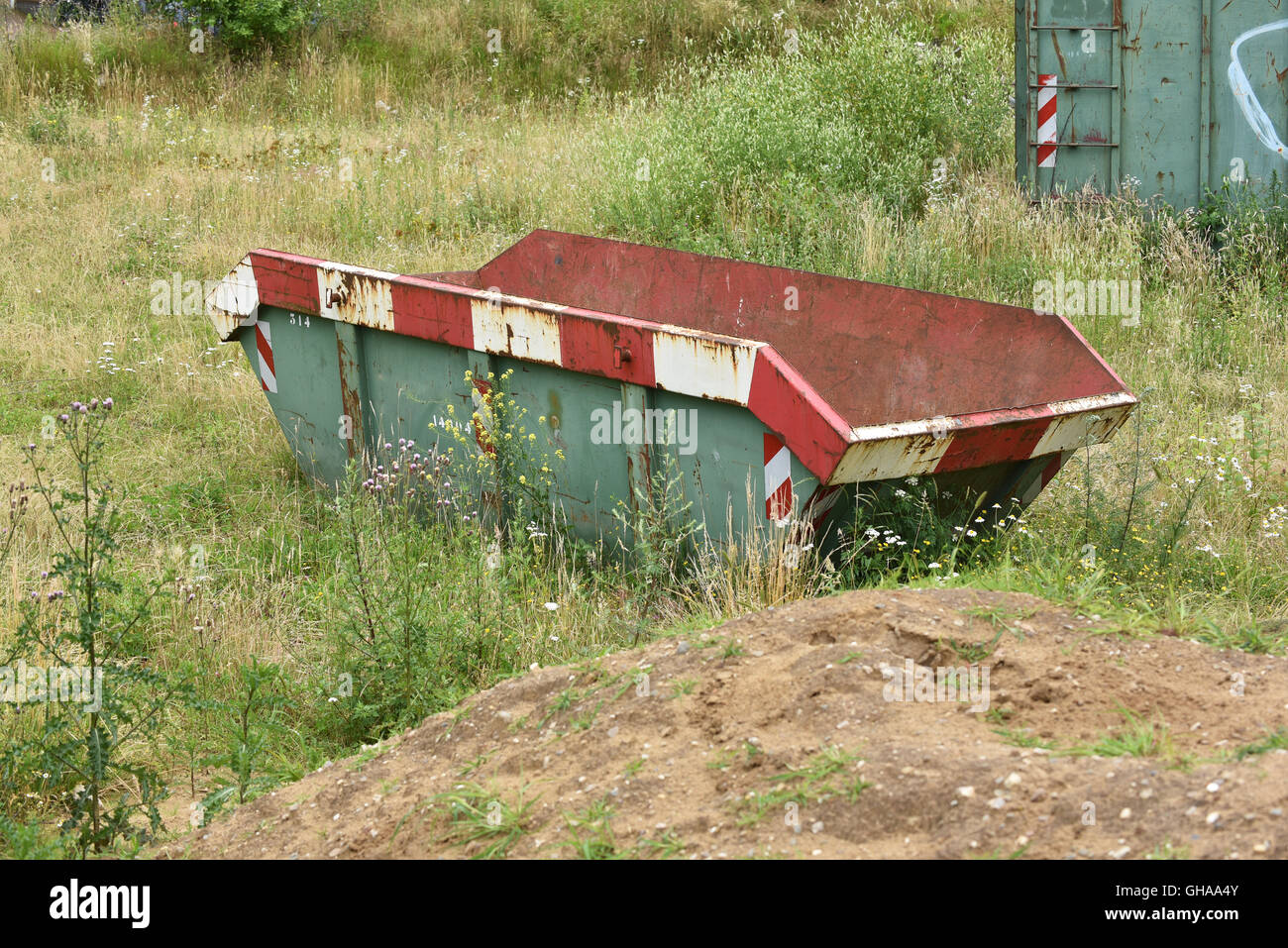 Dumpster cestino per rifiuti di costruzione su terreni a riposo Foto Stock