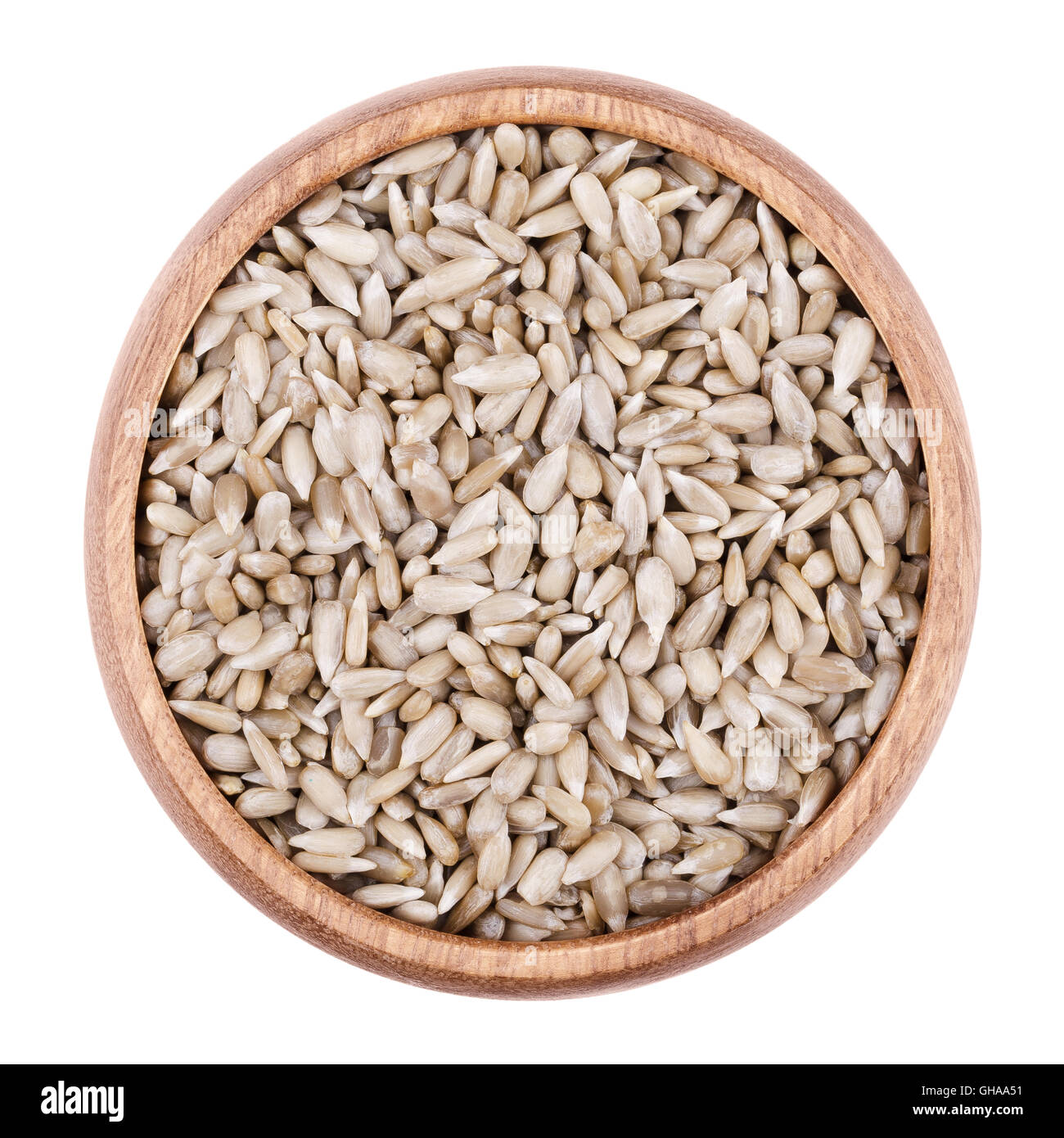 Semi di girasole in una ciotola di legno su sfondo bianco. Sgusciate materie commestibili sunflowerseeds di Helianthus annuus. Foto Stock