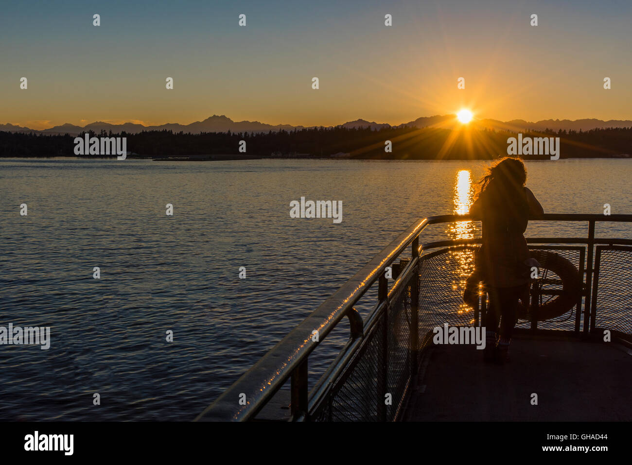 Giovane ragazza a guardare il tramonto sulla Baia di Elliott dal traghetto, Seattle, Washington, Stati Uniti d'America Foto Stock
