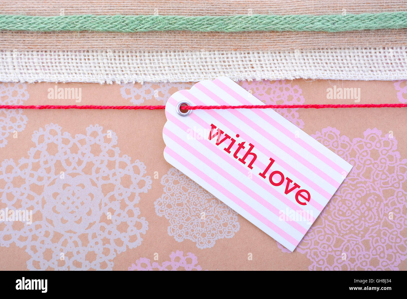 Close up di vintage confezione regalo con nastri multipli e tag regalo su floral stampata marrone naturale della carta. Foto Stock