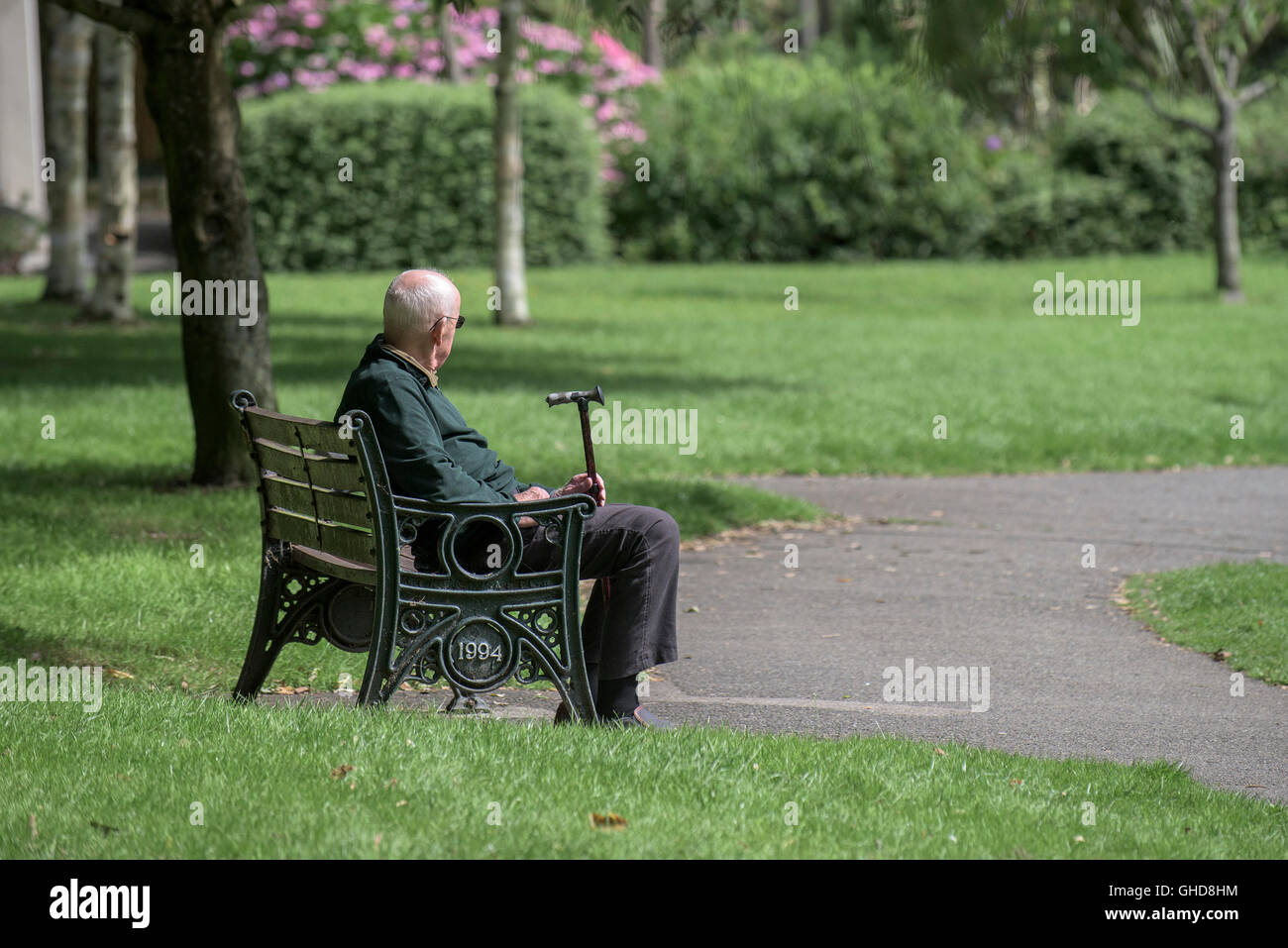 Un uomo anziano si siede da solo in Trenance Gardens in Newquay, Cornwall. Foto Stock