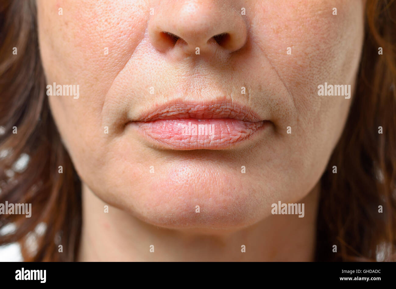 Primo piano sulla bocca di mezza età brunette donna con la sua bocca chiusa e una espressione seria Foto Stock